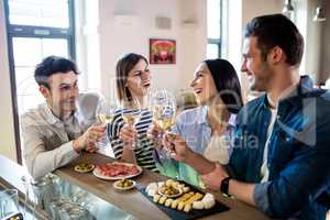 Young friends enjoying wine and food at counter