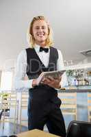 Waiter using digital tablet in restaurant