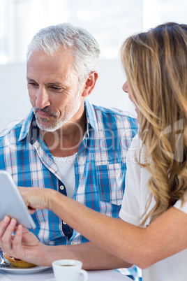 Woman showing digital tablet to man