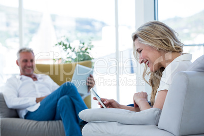 Smiling woman using mobile phone by man holding laptop