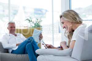 Smiling woman using mobile phone by man holding laptop
