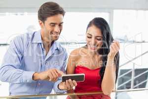 Happy couple using mobile phone in cafe