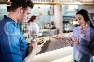 Man and woman using mobile phone by counter