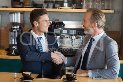 Businessmen shaking hands in cafÃ©