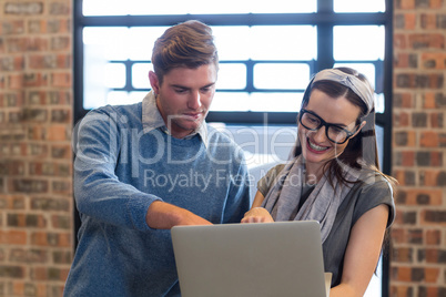 Young colleagues using laptop in office