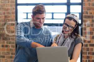 Young colleagues using laptop in office