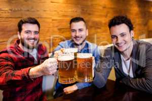 Portrait of male friends toasting beer at restaurant