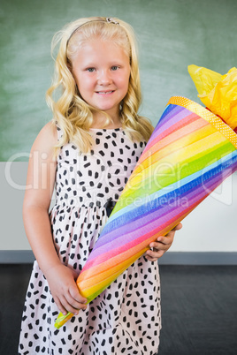 Portrait of smiling schoolgirl holding gift in classroom