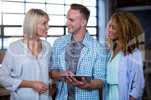 Business people smiling while discussing over digital tablet