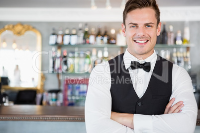 Portrait of waiter standing at bar counter