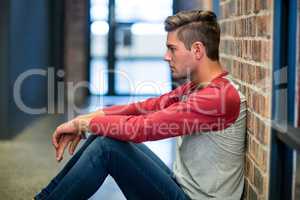 Stressed man sitting by wall