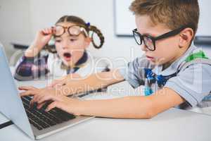 School kids using a laptop in classroom