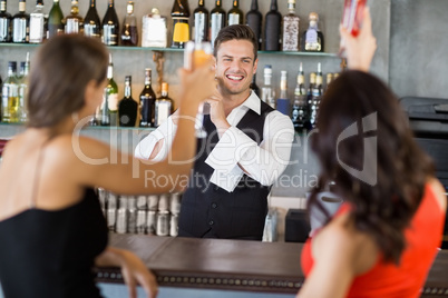 Two women toasting their glasses at bar counter