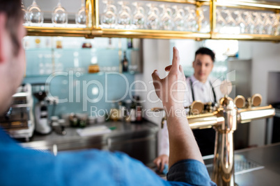 Man gesturing while talking with bartender