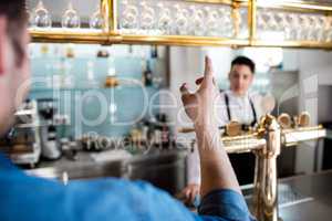 Man gesturing while talking with bartender
