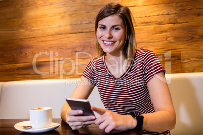 Young woman using cellphone in restaurant