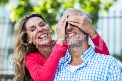 Mature woman covering eyes of man