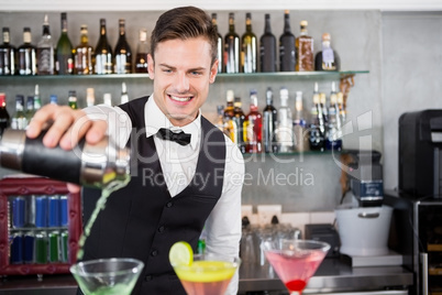 Waiter pouring cocktail into glasses