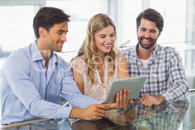 Smiling woman and two men using digital tablet