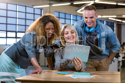 Business people smiling while discussing over tablet computer