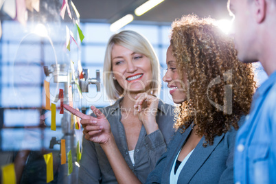 Businesswoman pointing on sticky note while explaining colleague