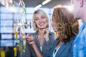 Businesswoman pointing on sticky note while explaining colleague