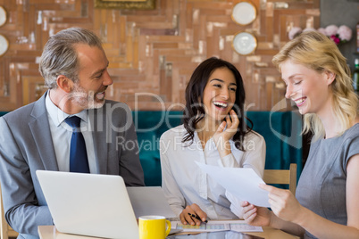 Business colleagues discussing on report with laptop on table