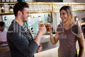 Young couple toasting beer mug by counter