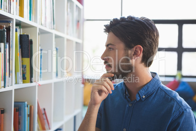 School teacher selecting book from bookshelf