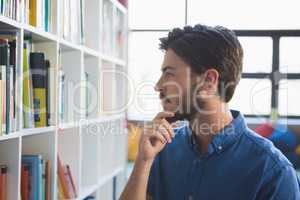 School teacher selecting book from bookshelf