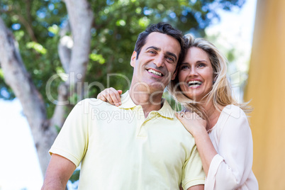 Happy couple standing against tree