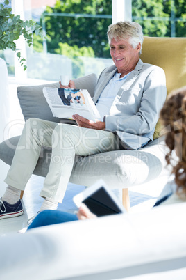 Man by woman reading newspaper at home