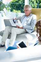 Man by woman reading newspaper at home