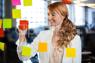 Businesswoman writing on adhesive notes
