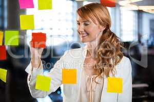 Businesswoman writing on adhesive notes