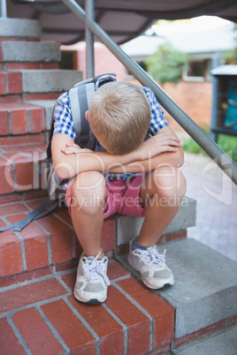 Sad schoolboy sitting alone on staircase