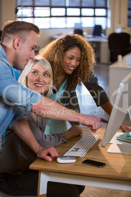 Business people discussing over computer at desk