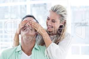 Mid adult woman covering eyes of man