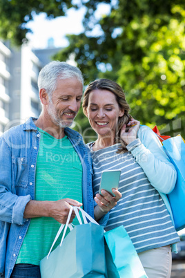 Smiling couple using mobile phone in city