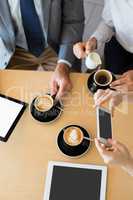 Colleagues having a cup of coffee while using mobile phone and d