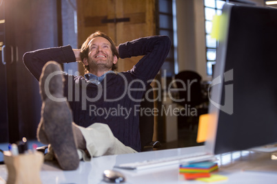 Businessman smiling while relaxing by desk