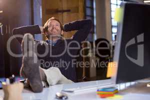 Businessman smiling while relaxing by desk