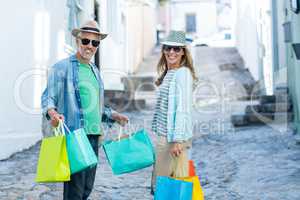 Mature couple holding shopping bags on street
