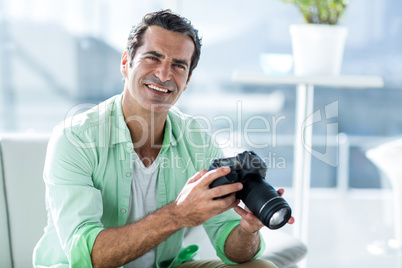 Mid adult man holding camera at home