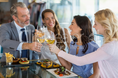 Happy business colleagues toasting beer glasses while having lun