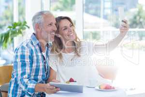Mature couple taking selfie in restaurant