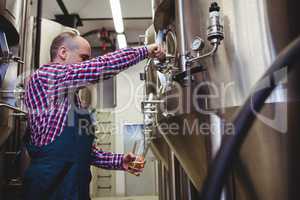 Manufacturer filling beer from storage tank at brewery