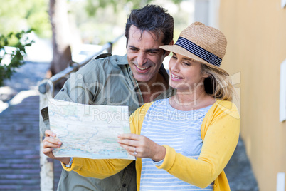 Couple looking in map while standing on walkway