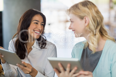 Two beautiful women interacting with each other while using lapt