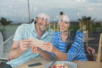 Couple using mobile phone in cafeteria
